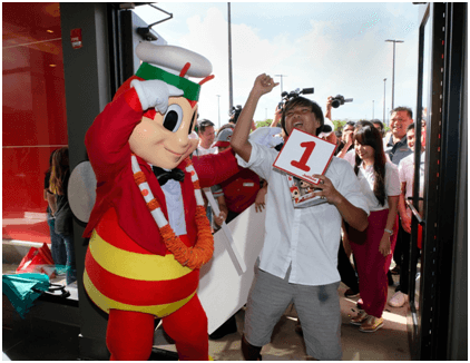 FIRST CUSTOMER. Landon Laureano, who stood in line for 12 hours to be the first customer at the new Jollibee restaurant in Dededo, is greeted by Jollibee as he enters on its opening day on April 6, 2019. Photo courtesy of Jollibee 