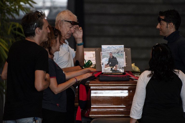 FUNERAL. Relatives pray and pay their respects near the coffin of a victim of the Morandi bridge's collapse, at a funerary home installed at the fairground in Genoa, on August 17, 2018. Photo by Marco Bertorello/AFP  