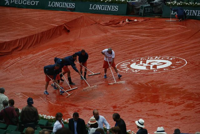 Workers prepare the Court of Philippe Chatrier to restart the match of Serena Williams against Kristina Mladenovic after a rain interruption during the women's single third round at the French Open tennis tournament.​​​​ Photo by ROBERT GHEMENT/EPA 