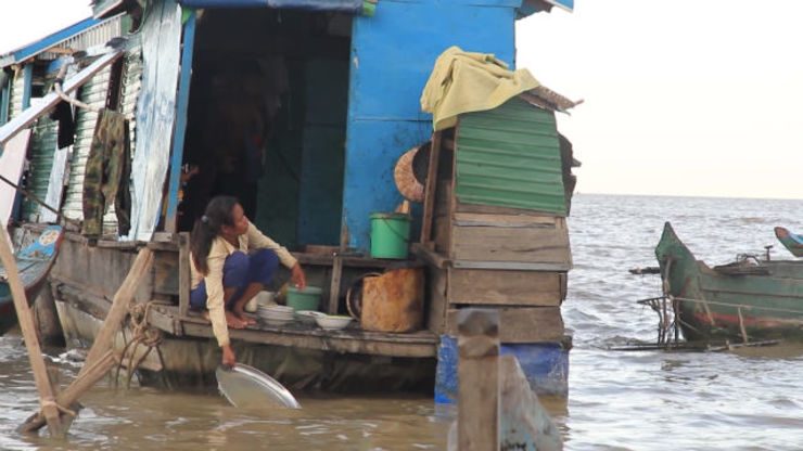 UNSANITARY. A resident of a floating village uses the river water to wash her dishes. 