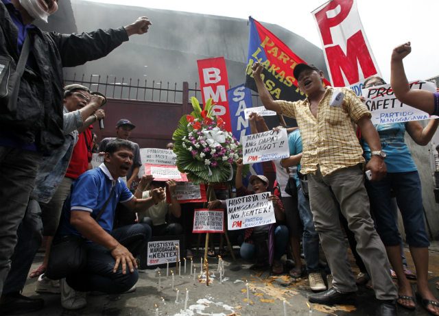 PROTEST. Filipino workers offer flowers as they stage a demonstration at the gate of a burnt footwear factory in Valenzuela city, east of Manila, Philippines, May 15 2015. Photo by Francis R. Malasig/EPA 