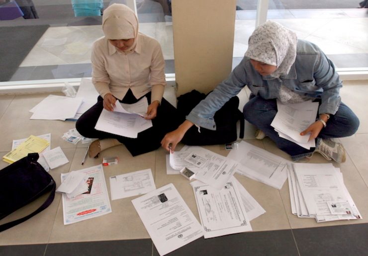 SKILLED. Two Indonesian job seekers prepare their application on the floor during a job fair in Jakarta. File photo by EPA