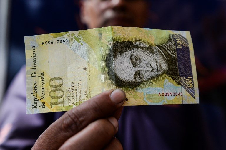 VENEZUELA'S BOLIVAR. A man shows a new one hundred thousand-Bolivar-note in Caracas on November 9, 2017. Photo by Federico Parra/AFP 
