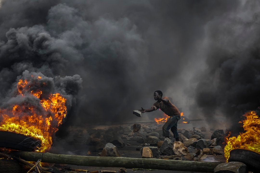 DEFIANCE. A Burundian protester throws from a burning barricade during an anti-government demonstration in the capital Bujumbura, Burundi, 22 May 2015. Photo by Dai Kurokawa / EPA   