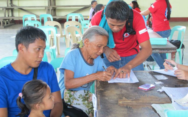 AID. A Red Cross volunteer helps a Yolanda survivor fill up the forms needed to receive a USD 220 cash grant. Photo from the PRC