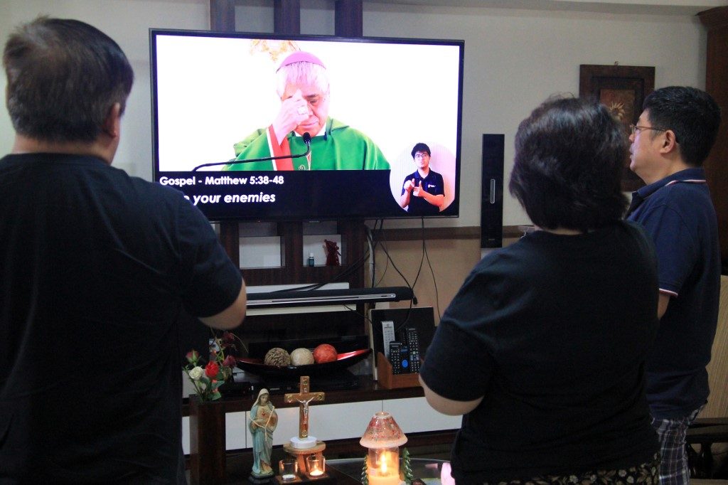 KEEPING THE FAITH. This photograph taken on February 23, 2020, shows Christian devotees listening to a pre-recorded mass by Singapore Archbishop William Goh on television inside their home as a protective measure to prevent the spread of the COVID-19 coronavirus in Singapore. File photo by Martin Abbugao/AFP  