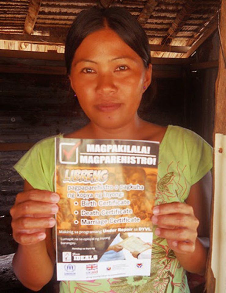 FREE REGISTRATION. A Yolanda survivor holds up a flyer promoting free registration and claiming of birth, death, and marriage certificates. Photo by IDEALS, Inc.