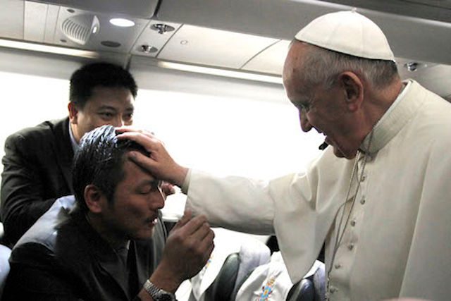 FLYING WITH THE POPE. Pope Francis touches the head of a Filipino cameraman aboard the papal plane. Photo by Joe Torres