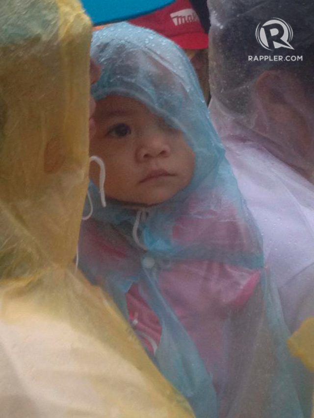 A baby joins in the line, under the rain, to enter the Pope Francis Center for the Poor in Palo