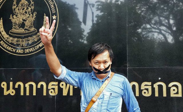 IN PROTEST. Thai journalist Pravit Rojanaphruk flashes a V-sign as he stands with his mouth taped outside a military base in Bangkok where he had been summoned by the junta on May 25, 2014. AFP PHOTO 