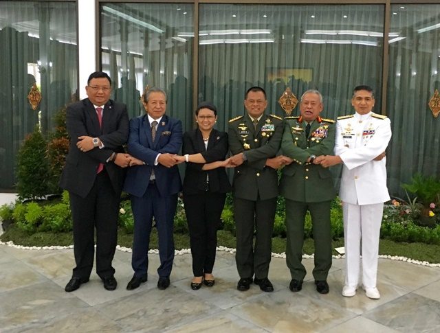 PERTEMUAN TRILATERAL. Menteri Luar Negeri Retno Marsudi (ketiga dari kiri) bergandengan tangan khas ASEAN dengan Menlu dari Filipina dan Malaysia serta panglima angkatan bersenjata dari negara tersebut. Foto oleh Kemlu 