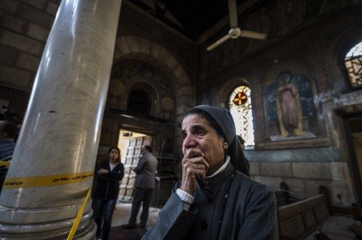Seorang biarawati di Gereja Saint peter dan Saint Paul di Kairo bersedih atas ledakan bom yang terjadi saat misa pada Minggu, (11/12). Foto oleh geKHALED DESOUKI / AFP 