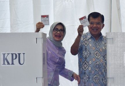 Wakil Presiden Jusuf Kalla (kanan) didampingi istri Mufidah Jusuf Kalla menunjukkan surat suara ketika memberikan suara pada Pilkada DKI Jakarta putaran kedua di TPS 3 Pulo, Kebayoran Baru, Jakarta, Rabu (19/4). Foto oleh Wahyu Putro/ANTARA 