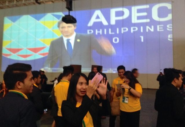 SELFIE. Members of the crowd at IMC take selfies with an image of Canadian Prime Minister Justin Trudeau in the background. Photo by Katerina Francisco/Rappler 