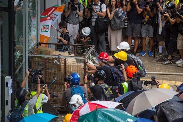 PROTEST. Protesters try to push a metal cart through a closed entrance at the government headquarters in Hong Kong on July 1, 2019 on the 22nd anniversary of the city's handover from Britain to China. Photo by Vivek Prakash/AFP 