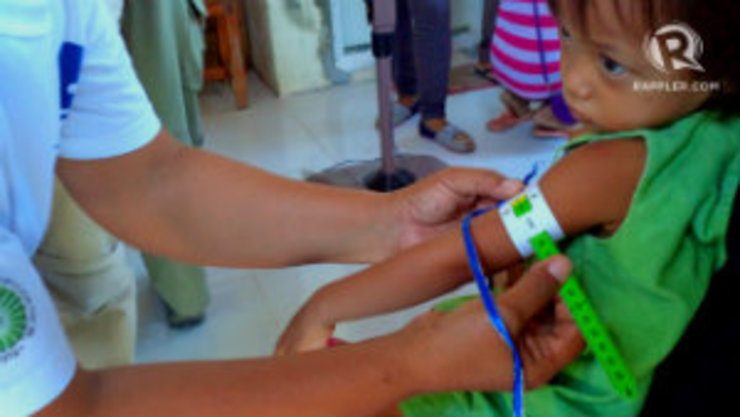 A barangay health worker uses MUAC tape