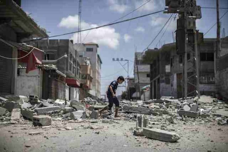A young Palestinian boy walks over debris from a house that was destroyed overnight in an airstrike in Deir Al Balah, central Gaza Strip, July 2014. File photo by Oliver Weiken/EPA