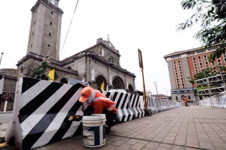 A worker paints the barricades that have been set up around the Manila Cathedral for the papal visit. Photo by Pat Nabong