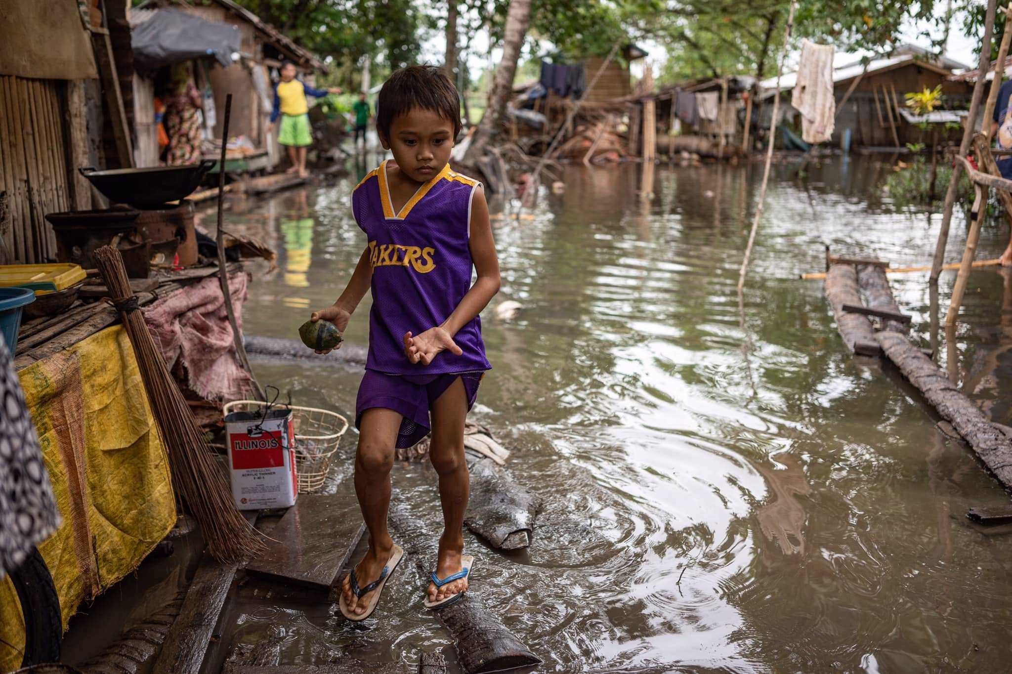 PLAYTIME. A child walks on a makeshift bridge while playing in their flooded evacuation site in Barangay Pagatin. Photo from Oxfam in the Philippines  