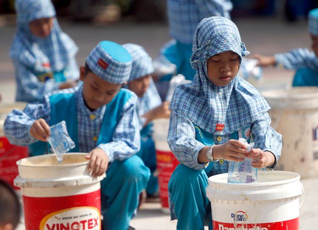 HUJAN BUATAN. Siswa sekolah di Palembang ini menuang garam dalam ember berisi air untuk kemudian diuapkan, 17 September 2015. Tujuannya adalah menciptakan awan hujan. Foto oleh Adi Weda/EPA 