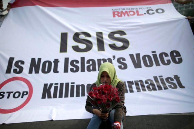 NOT ISLAM'S VOICE. An Indonesian journalist holds flowers as she sits in front of a banner during a protest against the killing of journalists by the Islamic State (IS) militant group, formerly known as the Islamic State of Iraq and al-Sham (ISIS), in Jakarta, Indonesia, 05 September 2014. Mast Irham/EPA