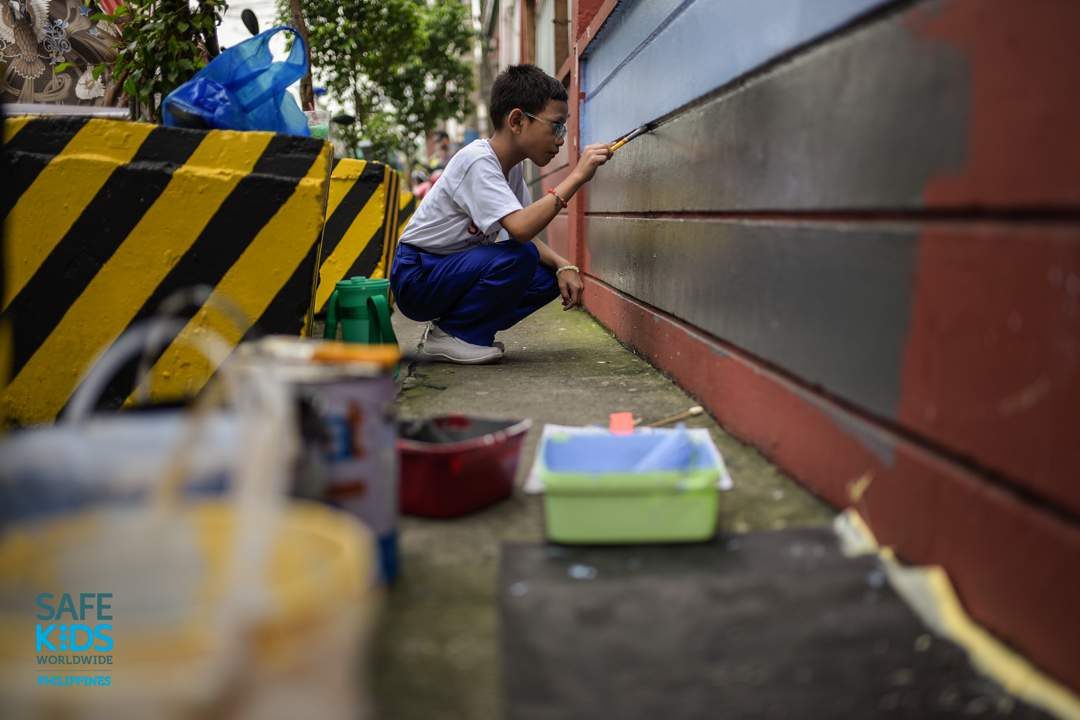 MURAL DESIGN. A student paints road safety-related art on the walls outside the school to raise more awareness for road users passing by the area. Photo by Heinz Reimann Orais  