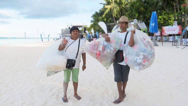 TRASH FOR CASH? Aling Jasmin and Mang Rene carry sacks of beer cans and drink bottles from May 1’s festivities. Photo by Krista Garcia/Rappler 