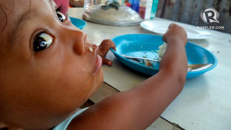 MEALS. A child living in a tent in Brgy San Jose, Tacloban eats fish and rice for lunch, his first meal for the day