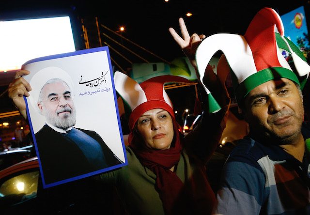Pasangan Iran menjunjung poster Presiden Hassan Rouhani ketika merayakan kesepakatan nuklir yang berpotensi mencabut sanksi bagi Iran, 14 Juli 2015. Foto oleh Abedin Taherkenareh/EPA 