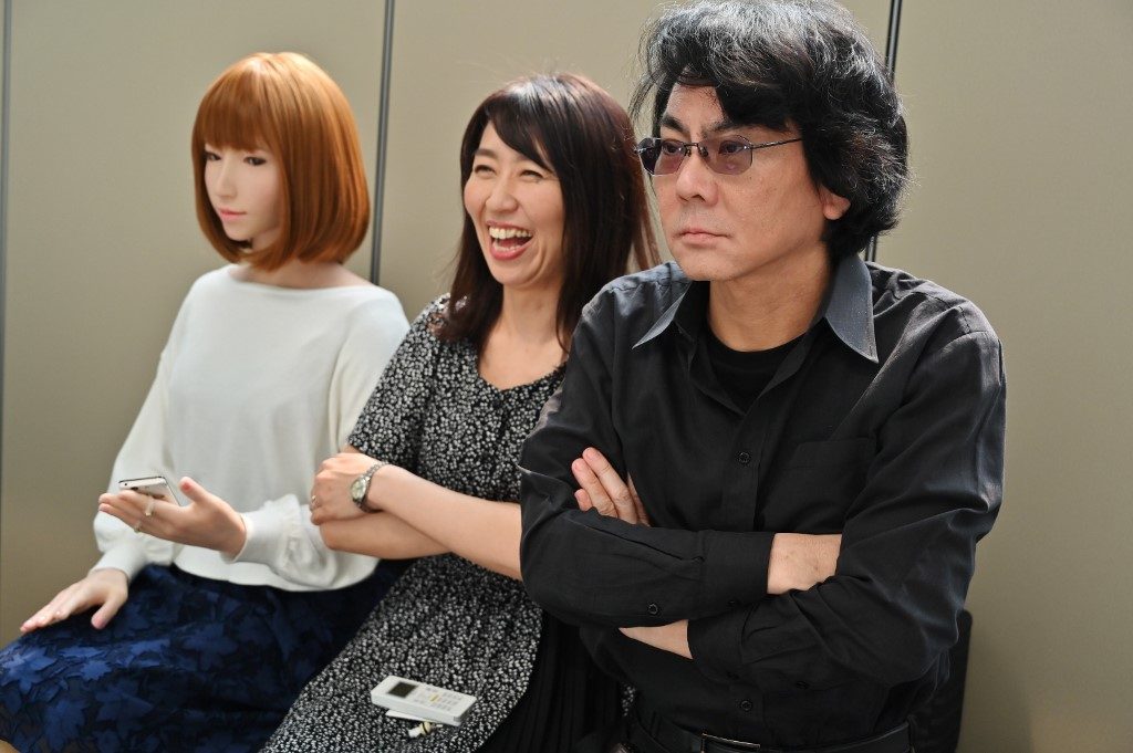 ROBOTICIST. This photo taken on June 16, 2019 shows robotician Hiroshi Ishiguro (right) and his assistant (center) posing next to one of his robots at his research center in Osaka. Photo by Charly Triballeau/AFP 