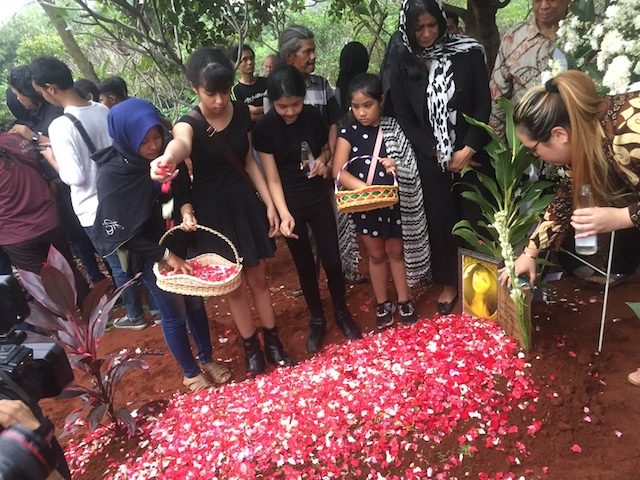TABUR BUNGA. Kedua anak perempuan Yana Zein menaburkan bunga di atas makam sang ibu. Foto oleh Rappler 