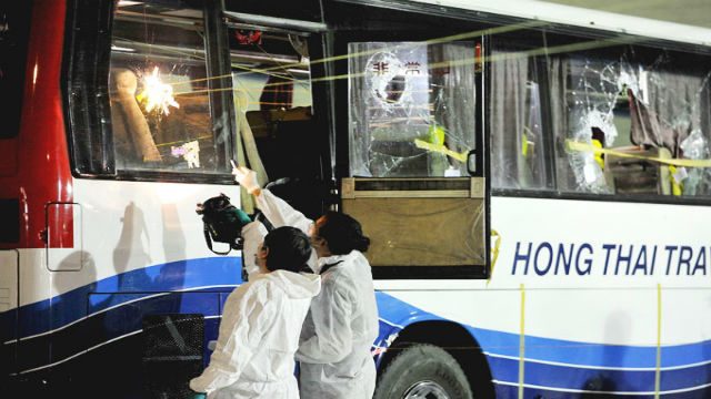HK HOSTAGES. Investigators examine broken glass of a bus where Hong Kong tourists were taken hostage in August 2010. File photo 