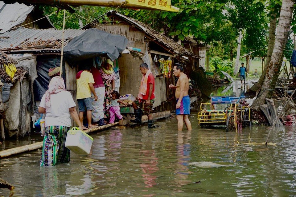WADING THROUGH THE FLOOD. Some IDPs wade through the ankle-deep floodwater in an evacuation center in Barangay Pagatin, Shariff Saydona Mustapha in Maguindanao. Photo from Oxfam in the Philippines  
