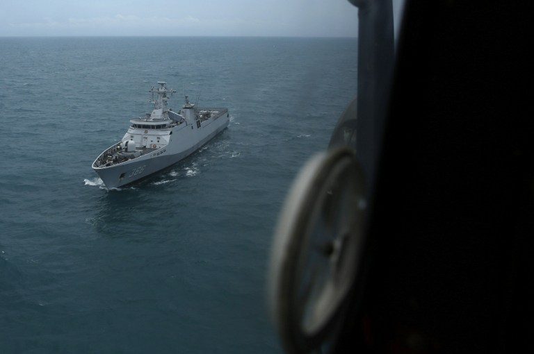 Indonesian navy ship 'KRI Sultan Hasanudin' is seen through the window of a Super Puma helicopter during a search operation for AirAsia flight QZ8501 over the Java sea on January 7, 2015.  Photo by Beawiharta/Pool/AFP