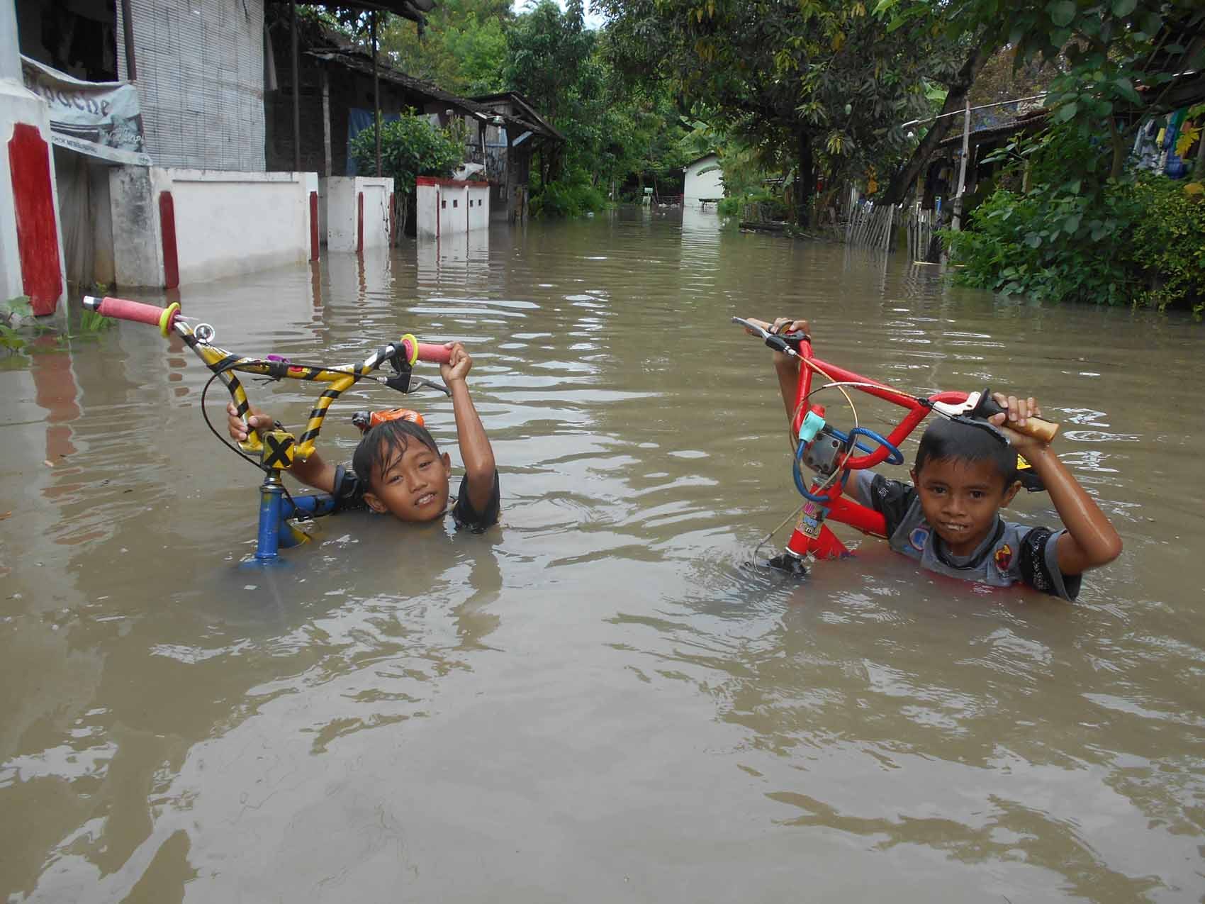 Dua anak menenteng sepeda saat banjir merendam hampir semua rumah di Dukuh Kaliwingko, RT 03/RW I, Madegondo Grogol, Sukoharjo. Foto oleh Fariz Fardianto/Rappler 