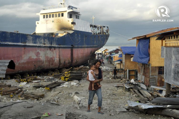 SAFETY FIRST. Mothers, fathers, and children reside around a grounded ship in Barangay Anibong in Tacloban City. Photo by Leanne Jazul/Rappler