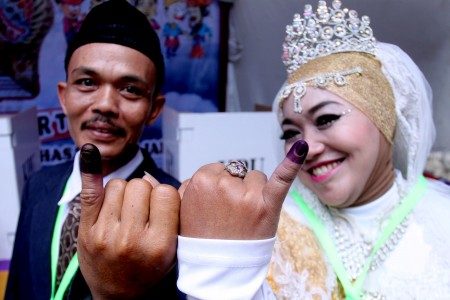 Petugas KPPS yang menggunakan kostum pernikahan menunjukkan jari setelah mencoblos di TPS 02, Cijantung, Jakarta Timur, Rabu (19/4). Foto oleh Yulius Satria Wijaya/ANTARA 