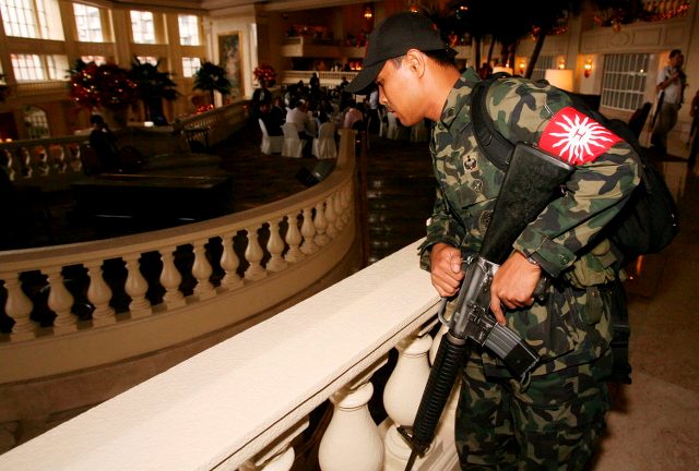 REBELLION. A rebel soldier stays inside the Manila Peninsula Hotel following a call to withdraw support for then president Gloria Macapagal-Arroyo. File photo by Dennis M. Sabangan/EPA