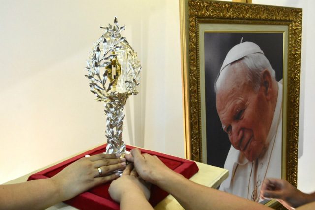 PRAYER INTENTIONS. Catholics touch the reliquary containing the blood relic of Pope Saint John Paul II, as they pray for their own intentions. Photo by Angie de Silva/Rappler 