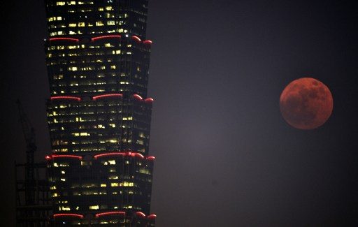 Penampakkan super moon di samping Gedung Taipei 101 building di Taipei, Senin (14/11). Foto oleh SAM YEH/AFP 
