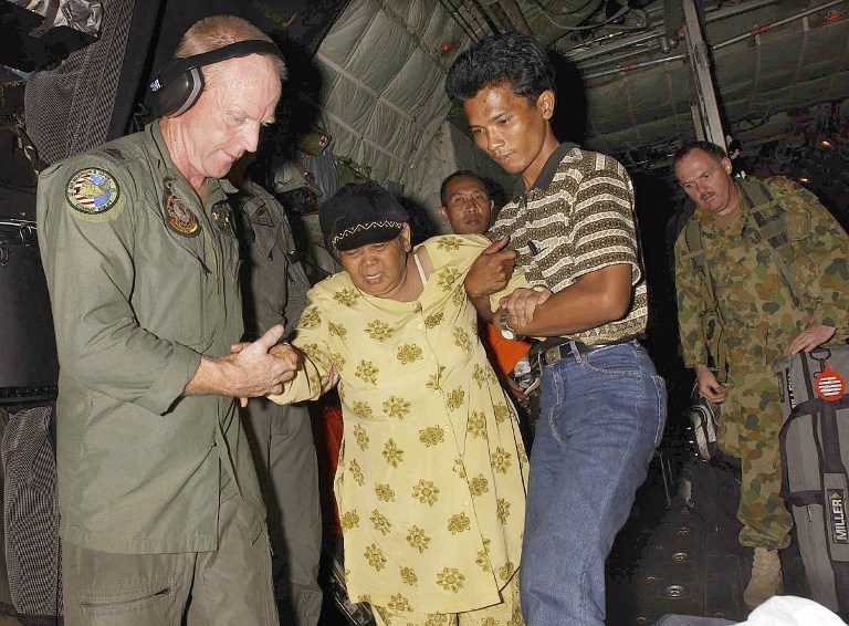 The world came to help. Here, Australian soldiers and locals assist an elderly survivor as she disembarks from an RAAF C-130 Hercules.