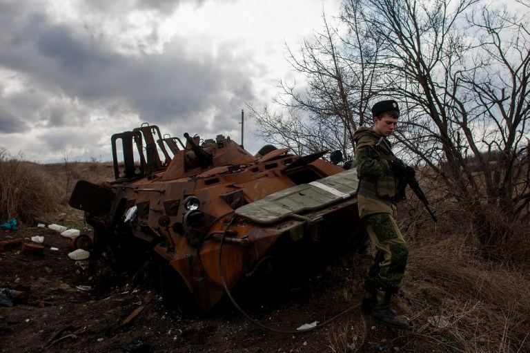 SEPARATIST. A pro-Russian rebel walks past a destroyed Ukrainian Armoured Personal Carrier (APC) not far from small Ukrainian city of Metalist, on March 23, 2015. Photo by Zurab Javakhadze / AFP     