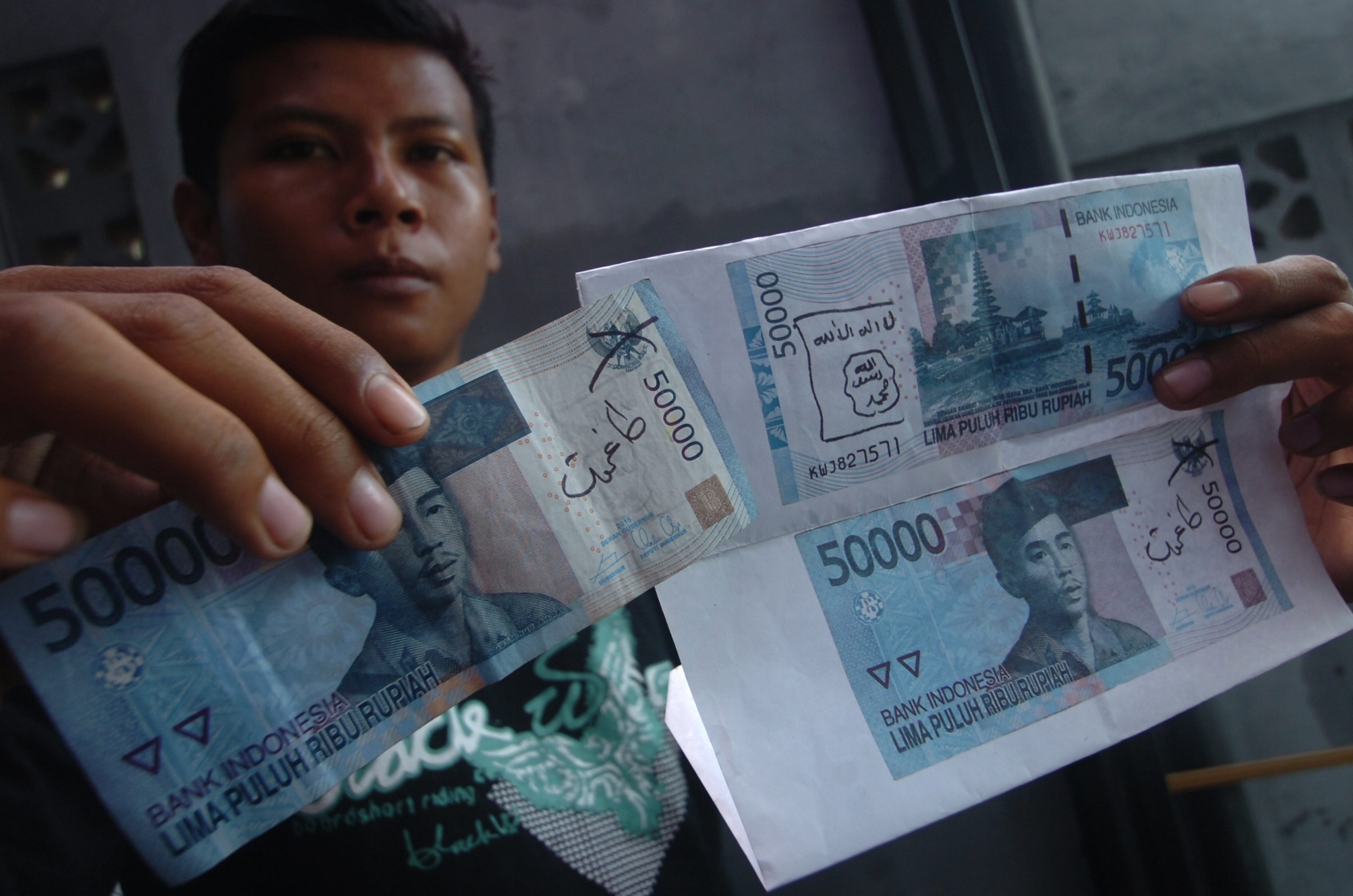 Warga menunjukkan temuan uang kertas yang dituliskan lambang ISIS di Kabupaten Ciamis, Jawa Barat, pada 27 Januari 2016. Foto oleh Adeng Bustomi/Antara 