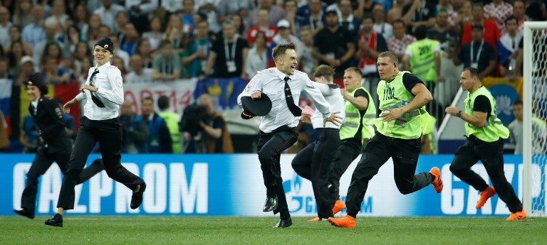 15 SECONDS OF FAME. Stewards remove pitch invaders claiming to be members of the feminist Russian band Pussy Riot. Photo by Odd Andersen/AFP  