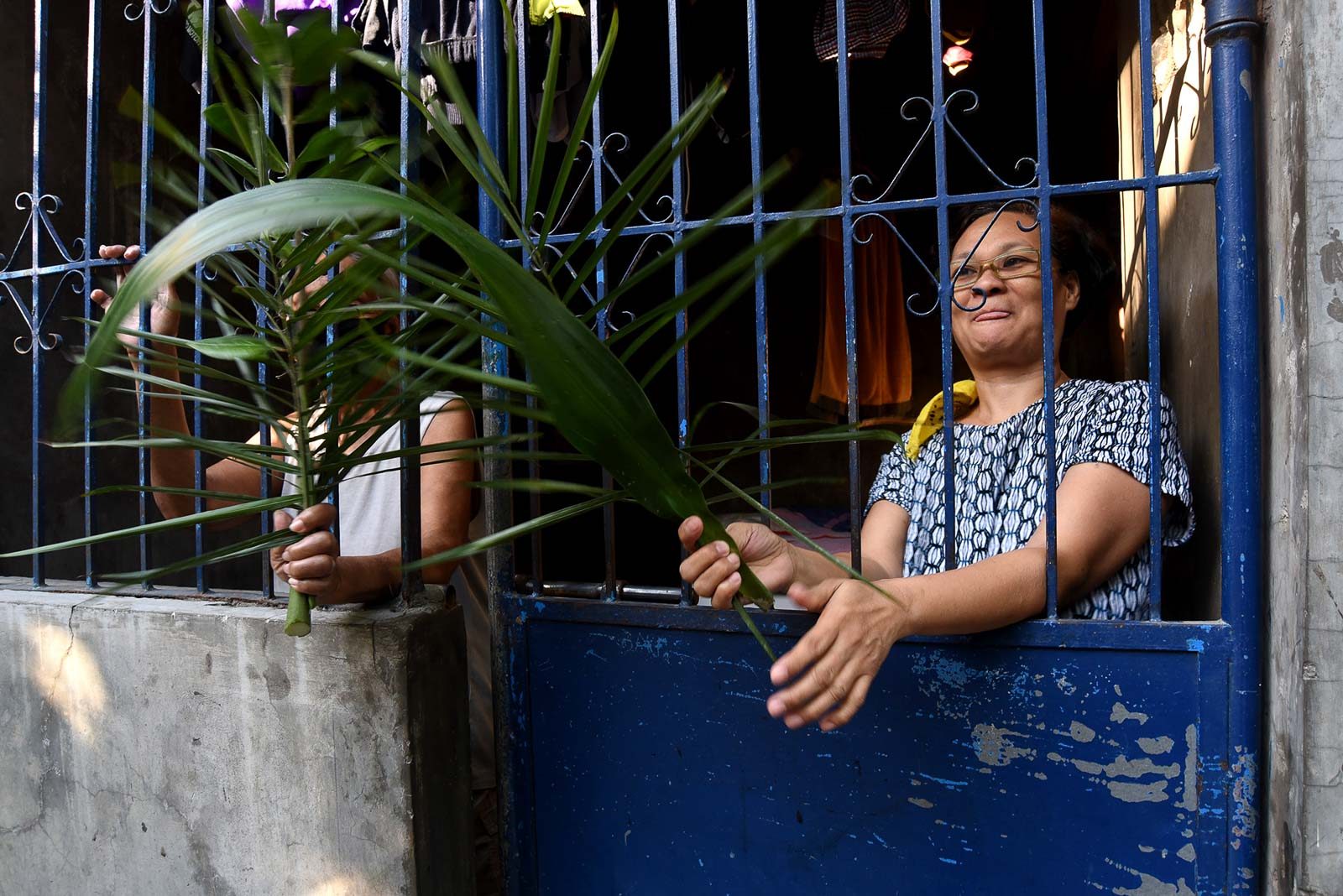 LOCKDOWN. In the safety of their homes, Catholics wait for priests to pass by to bless their palm fronds on Palm Sunday, April 5, 2020, as Luzon remains on lockdown due to the coronavirus pandemic. Photo by Angie de Silva/Rappler  