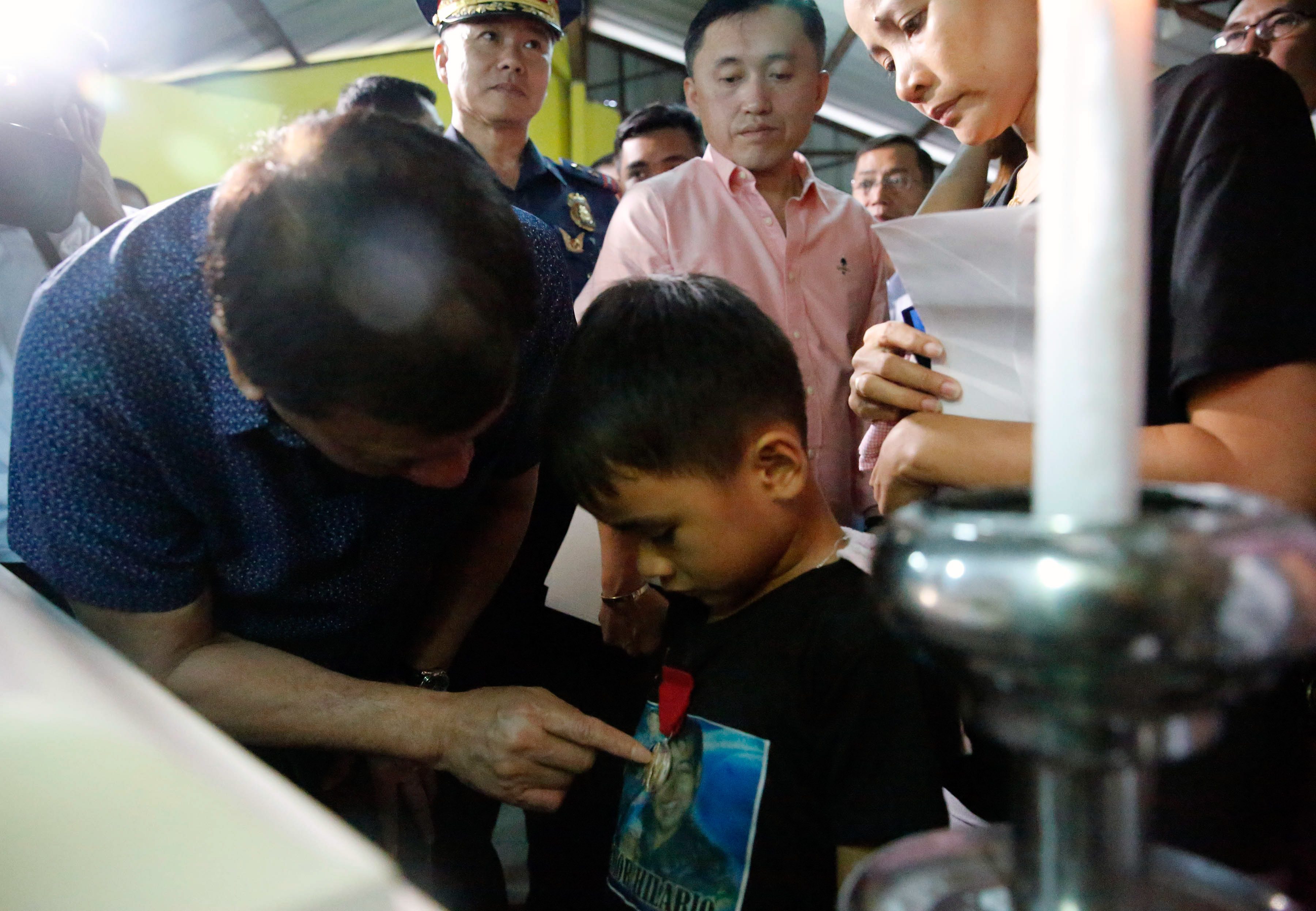TRIBUTE TO A FATHER. President Rodrigo Duterte pins the Order of Lapu-Lapu Kalasag Medal onto the shirt of 6-year-old Jun Hilario. Presidential photo 