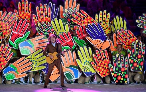 Penyanyi Brasil Lenine tampil dengan latar belakang dekorasi berbentuk tangan. Foto oeh Fabrice Coffrini/AFP 