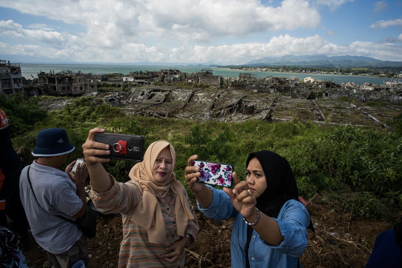 SOUVENIR. Guests at the groundbreaking ceremony take selfies with a ravaged Marawi in the background. 