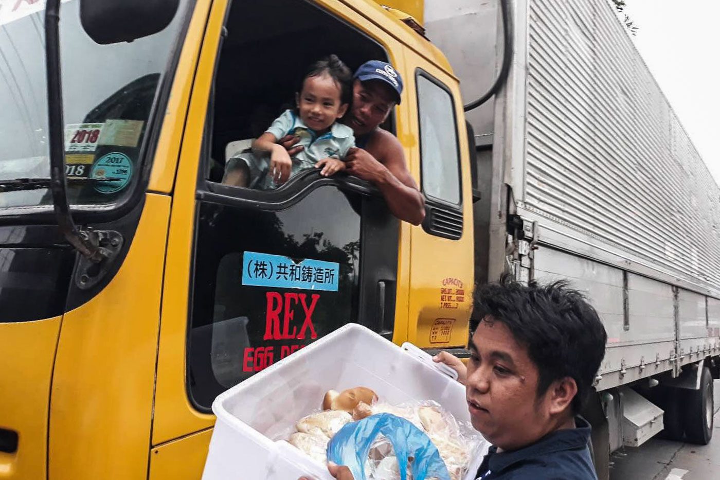 SHARING. An employee of the Land Transportation Office distributes noodles and other cooked meals to stranded motorists at the South Luzon Expressway. Photo from DOTr    