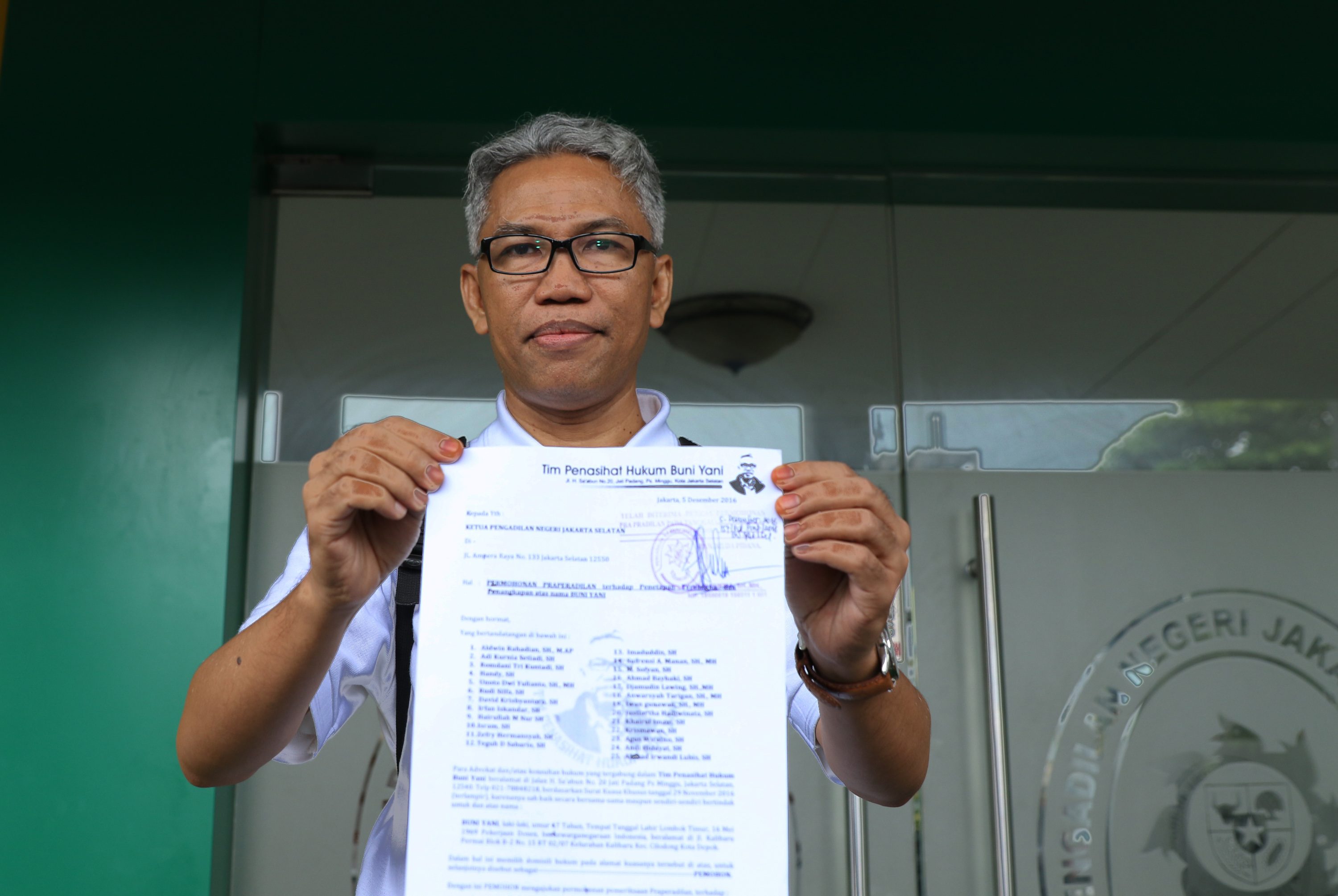 Tersangka kasus dugaan penyebaran kebencian, Buni Yani, menunjukkan surat permohonan Praperadilan di PN Jakarta Selatan, pada 5 Desember 2016. Foto oleh Reno Esnir/Antara 